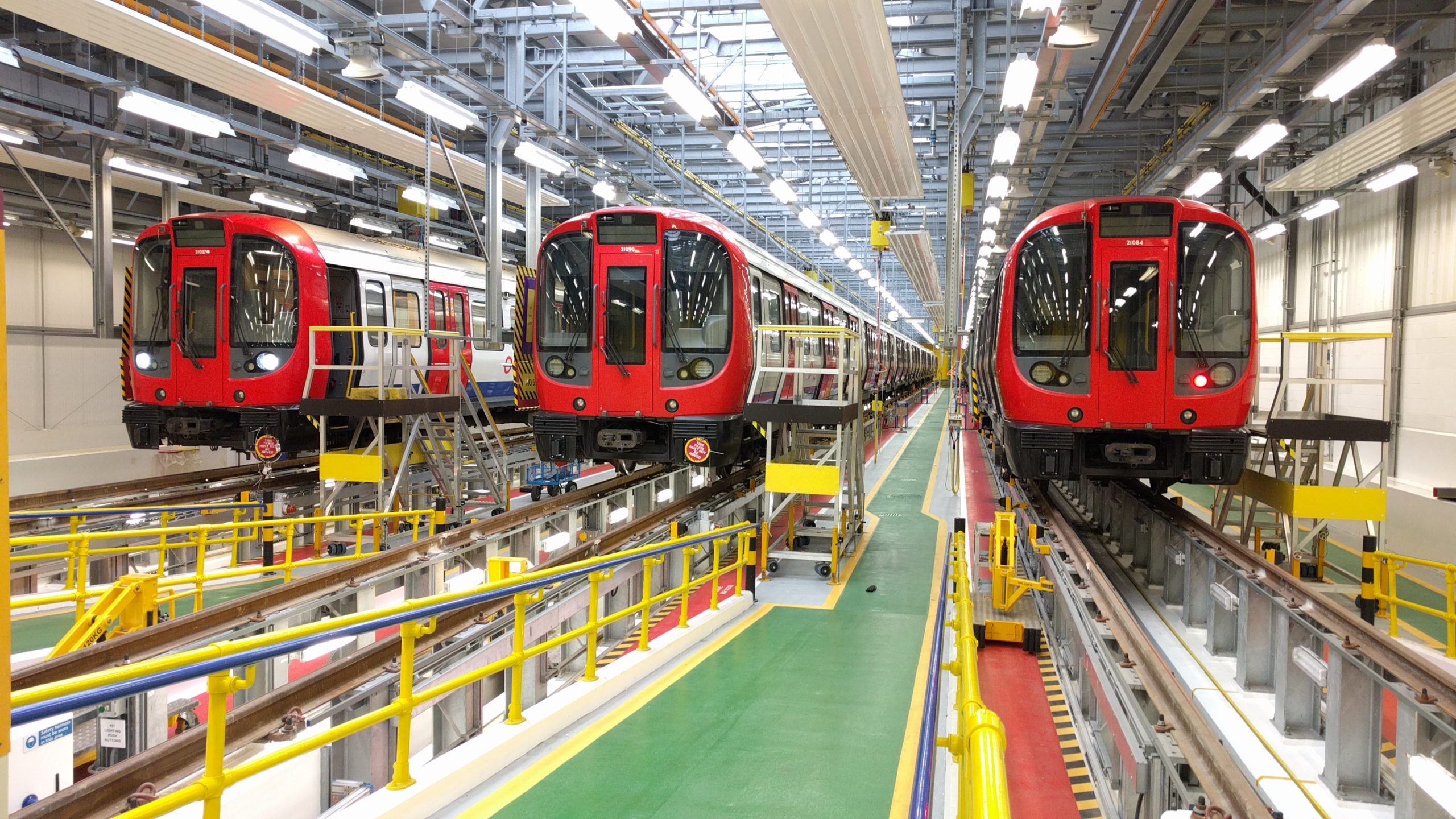 Image of three London Underground trains on elevated inspection tracks in a depot.